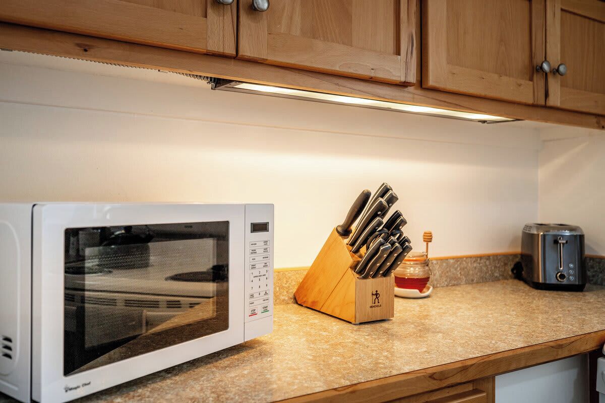 A kitchen with a white microwave, a knife block, and a toaster on the counter.