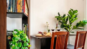 Un comedor con una mesa lista para dos personas, una estantería y una planta grande.