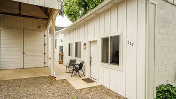 A white building with a gravel patio, a table with chairs, and a window with the number 517.