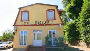 A two-story building with a yellow facade, a white door, and a small balcony. - Modernes Appartement mit Balkon, Wiek (Wiek)