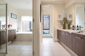 Un baño moderno con un espejo grande, muebles de madera oscura y una ventana que proporciona luz natural.