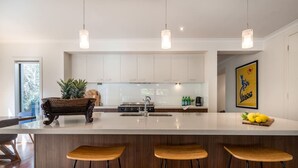 A modern kitchen with a central island, bar stools, and pendant lighting.