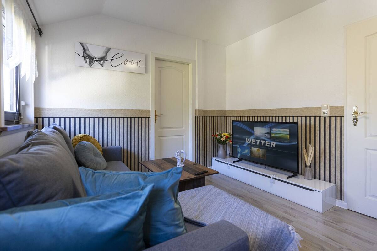 A modern living room with a sofa, a television, and a decorative wall piece.