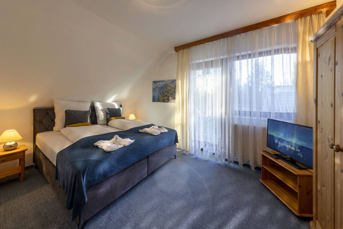 A hotel room with a bed, a TV, a lamp, and a painting on the wall.