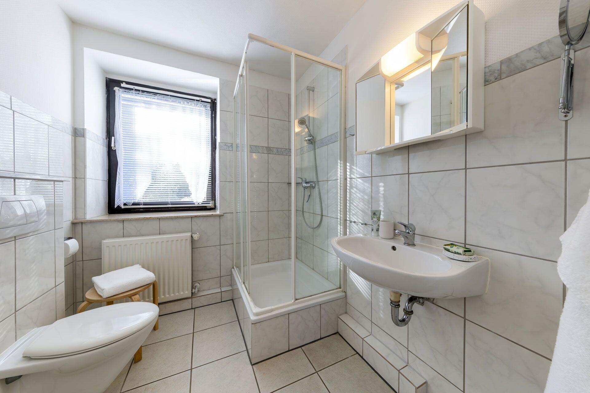 Een moderne badkamer met toilet, douche en wastafel.