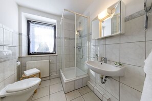 A modern bathroom with a toilet, a shower, and a sink. - AMAYA Hotel & Suites (Soltau)