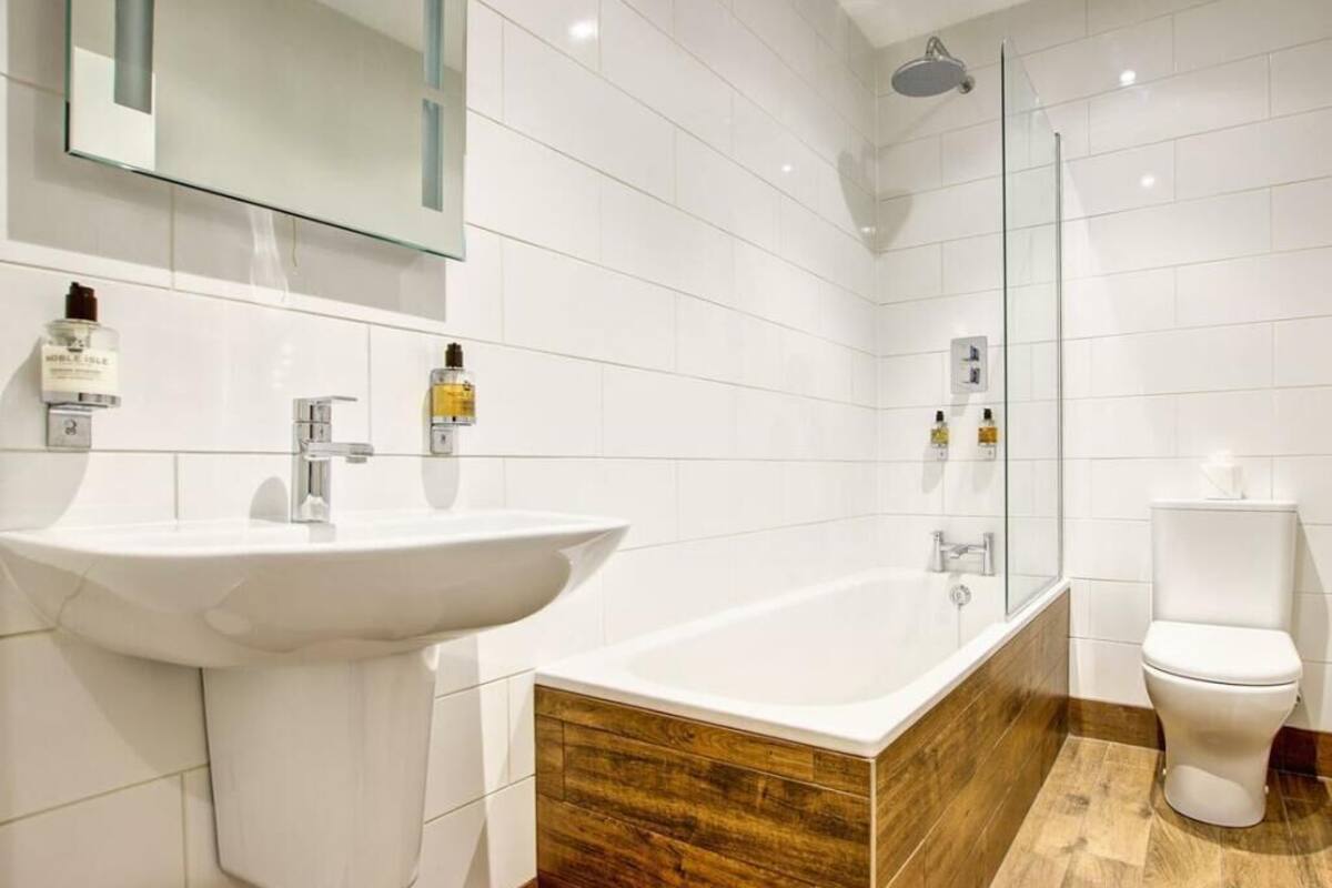A modern bathroom with a large white sink, a freestanding bathtub, and a toilet.