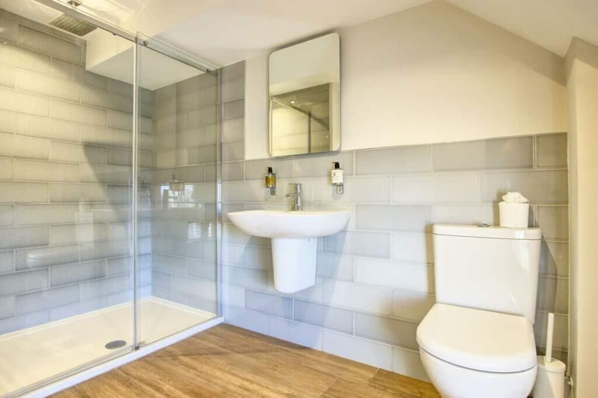 A modern bathroom with a glass shower enclosure, a white sink, and a toilet.