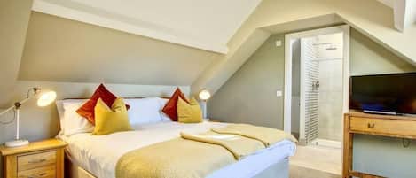 A bedroom with a bed, bedside tables, a TV, and a door leading to another room.