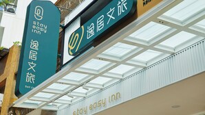 Une enseigne d’hôtel portant le nom « Stay Easy Inn » et un symbole indiquant la possibilité d’effectuer l’enregistrement soi-même.