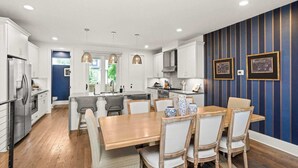 Une cuisine moderne avec des meubles blancs, un îlot central et des luminaires suspendus.