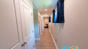 A hallway with white doors, a wooden floor, and blue curtains on the right wall.