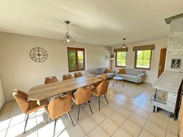 A spacious living area with a wooden dining table, multiple chairs, a sofa, and a fireplace.