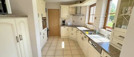 A kitchen with white cabinets, a tiled floor, a window, and a built-in oven.