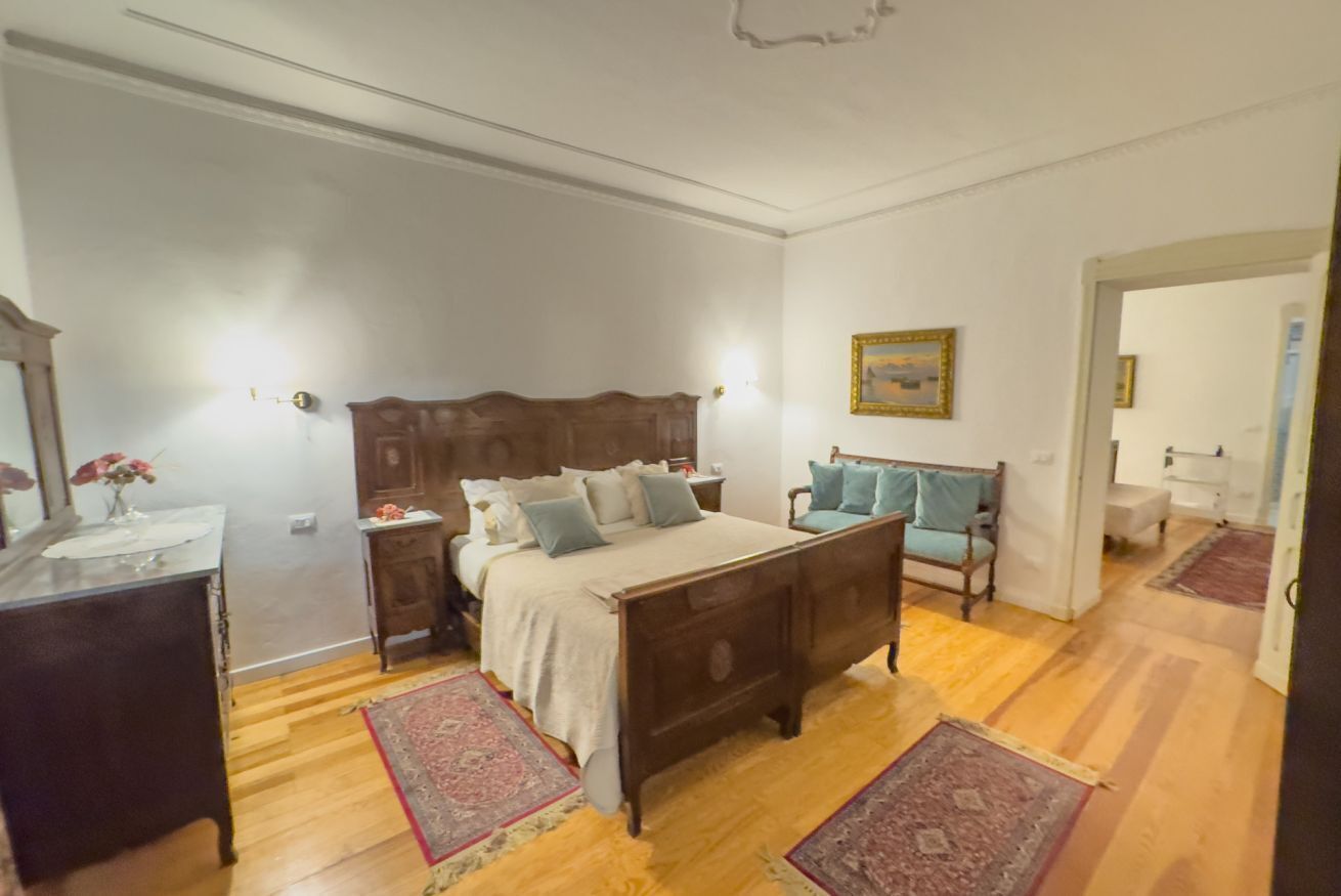 A bedroom with a wooden bed, bedside tables, a dresser, and a chair.