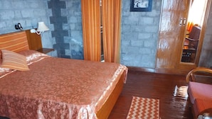Ein Schlafzimmer mit Bett, Holz-Kopfteil, Nachttischen, einem Spiegel und Blick auf einen Balkon.