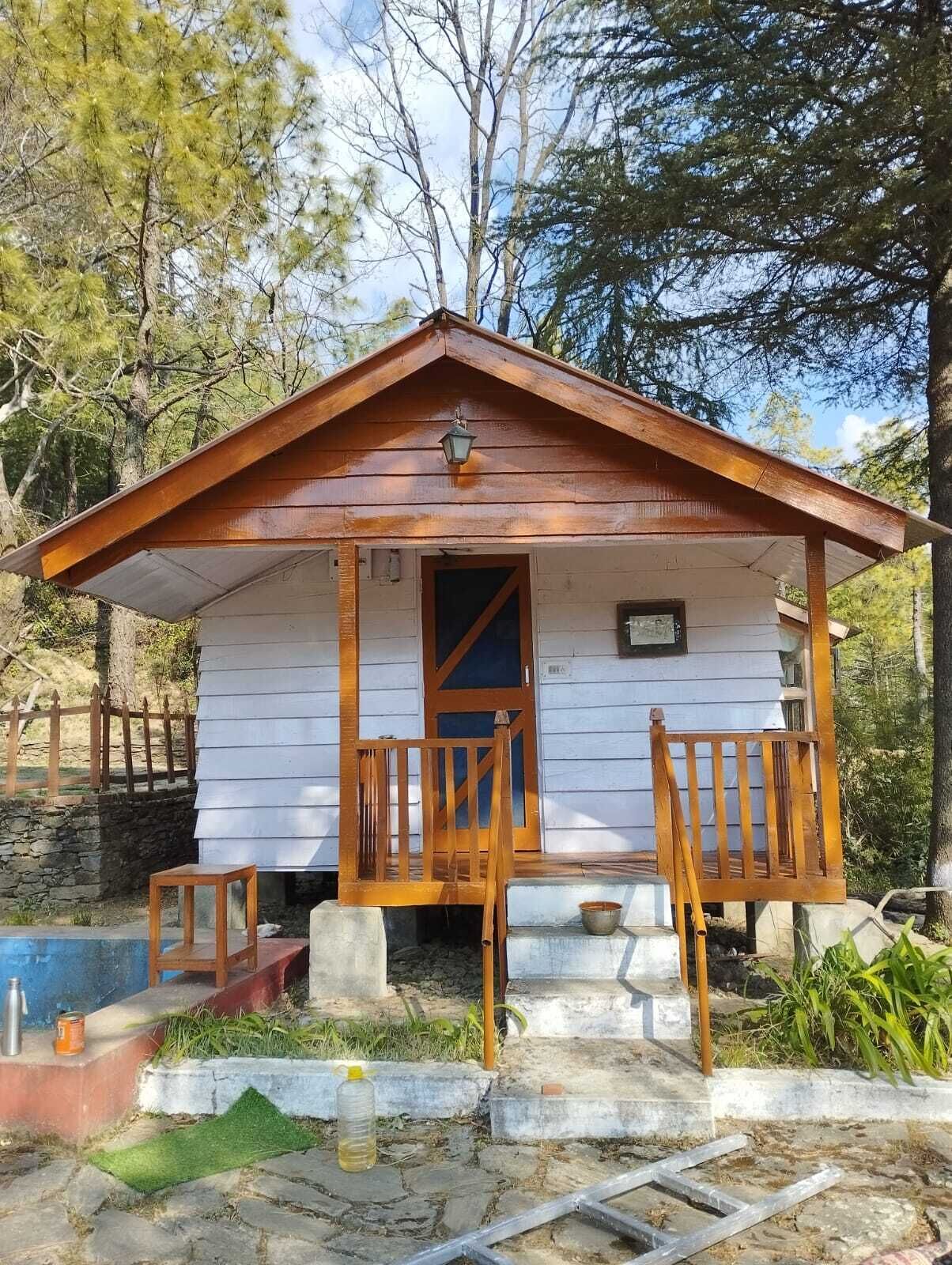 A small wooden cabin with a porch, a door, and a window.