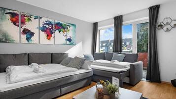 Ein modernes Wohnzimmer mit grauen Sofas, einem Couchtisch und einer Weltkarte als Wandbild.