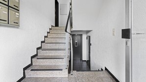 Una escala amb barana metàl·lica que porta a una porta a dalt.