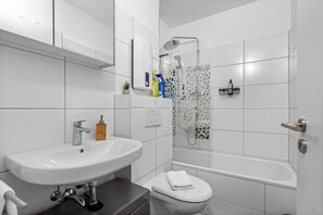 Un baño moderno con lavamanos, inodoro y ducha blancos.