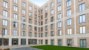 A multi-story building with a courtyard featuring a green lawn and a paved walkway. - For Students Only - Straits Meadow in Edinburgh City Centre - Campus Accommodation (Edinburgh)