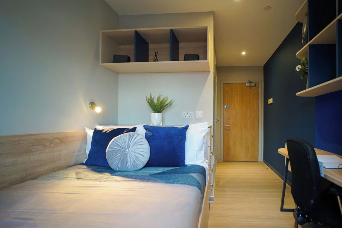 A modern bedroom with a bed, bedside tables, a desk, and a shelving unit.