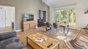 A spacious living area with a dining table, sofas, and a kitchen in the background. - Villas Odalys Collection Domaine de Lana by Interhome (Saint-Jean-de-Luz)