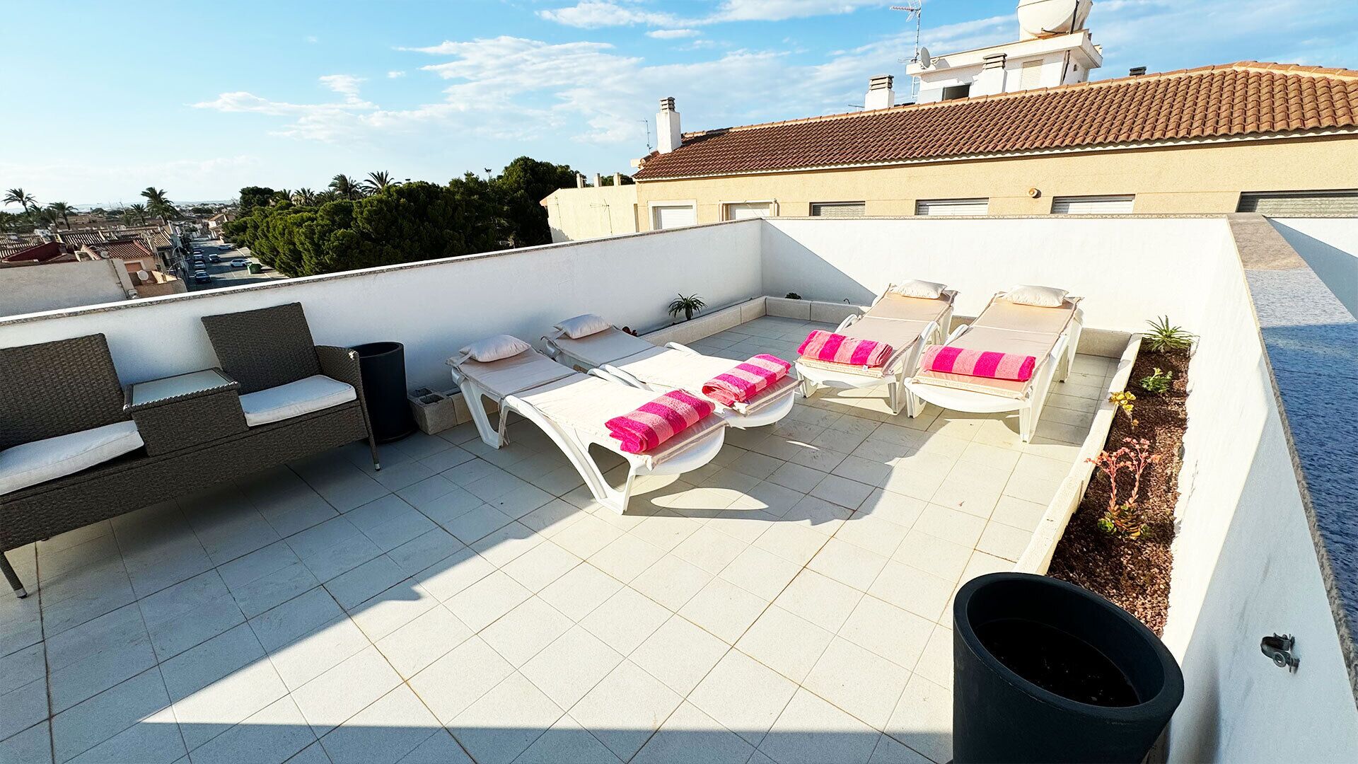 A rooftop terrace with lounge chairs, a sofa, and a dining table.