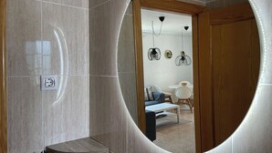 Une salle de bain moderne avec un grand miroir, un meuble-lavabo en bois et un luminaire.