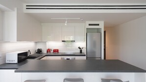 Een moderne keuken met witte kasten, een zwart aanrecht, een roestvrijstalen koelkast en een magnetron.