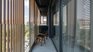A balcony with wooden slats, a glass door, and two wicker chairs. - LIV Athinum 1 - Luxury Apartment 3B (Athens)