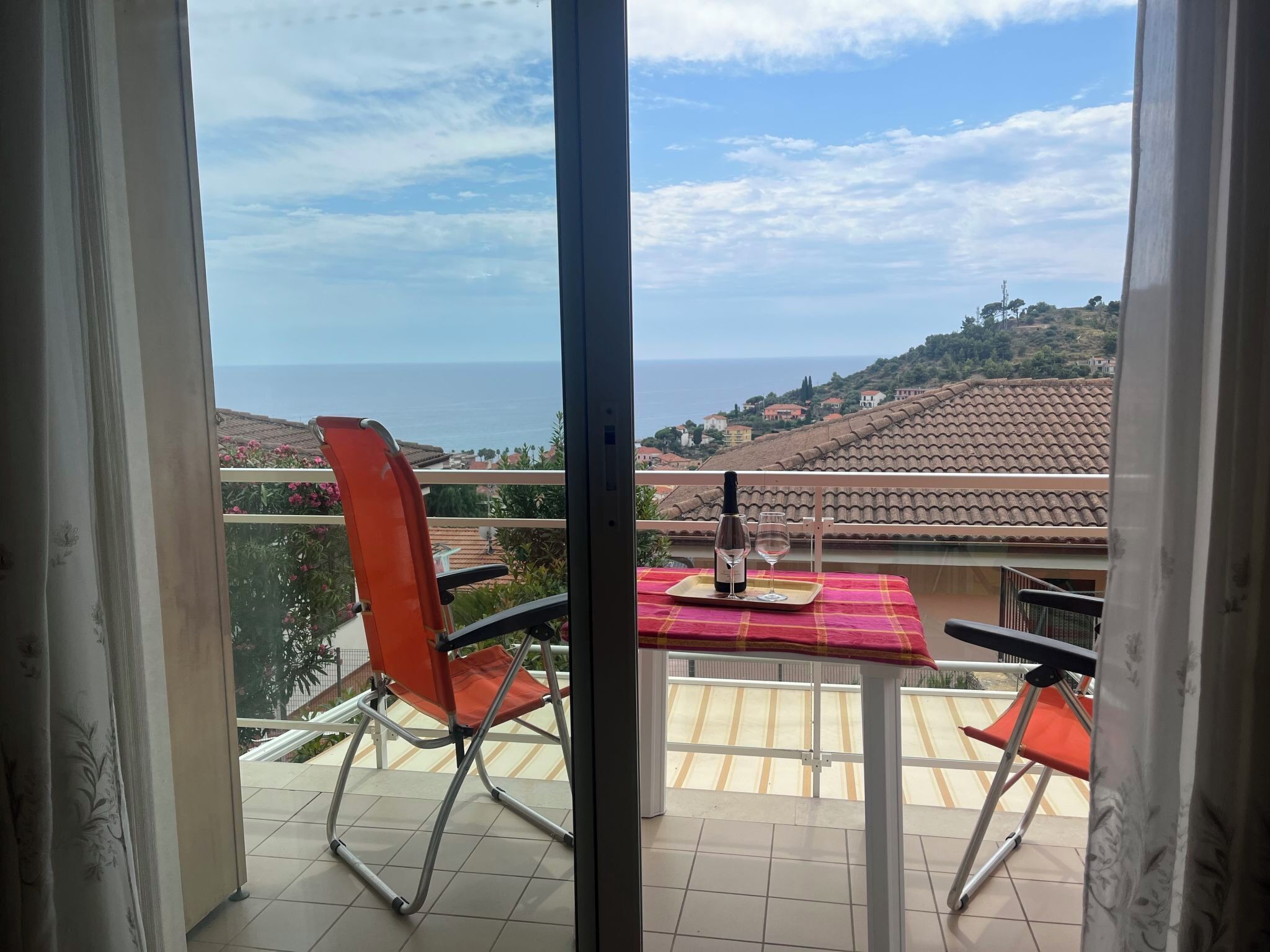 Ein Balkon mit Tisch für zwei Personen, mit Blick auf eine Küstenlandschaft.