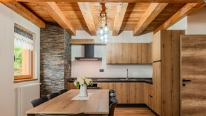 Una cucina moderna con mobili in legno, una parete decorata con pietra e un'area pranzo con tavolo e sedie in legno.
