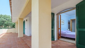 A room with a bed, a door leading to another room, and a view of the outside. - Holiday Villa for Complete Relaxation (Olbia)