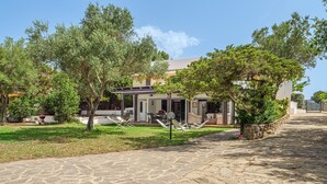 A stone-paved pathway leading to a building with a covered patio area and outdoor seating. - Holiday Villa for Complete Relaxation (Olbia)