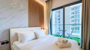 A hotel room with a large bed, a marble wall, a wooden panel, and a balcony with a view of a building.