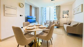 A modern living room with a dining area, a sofa, a TV, and a large window.