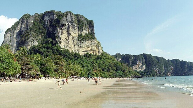 A beach with a large cliff and palm trees. - Syama V Ao Nang Beach Krabi, an Aspira Collection (Krabi)