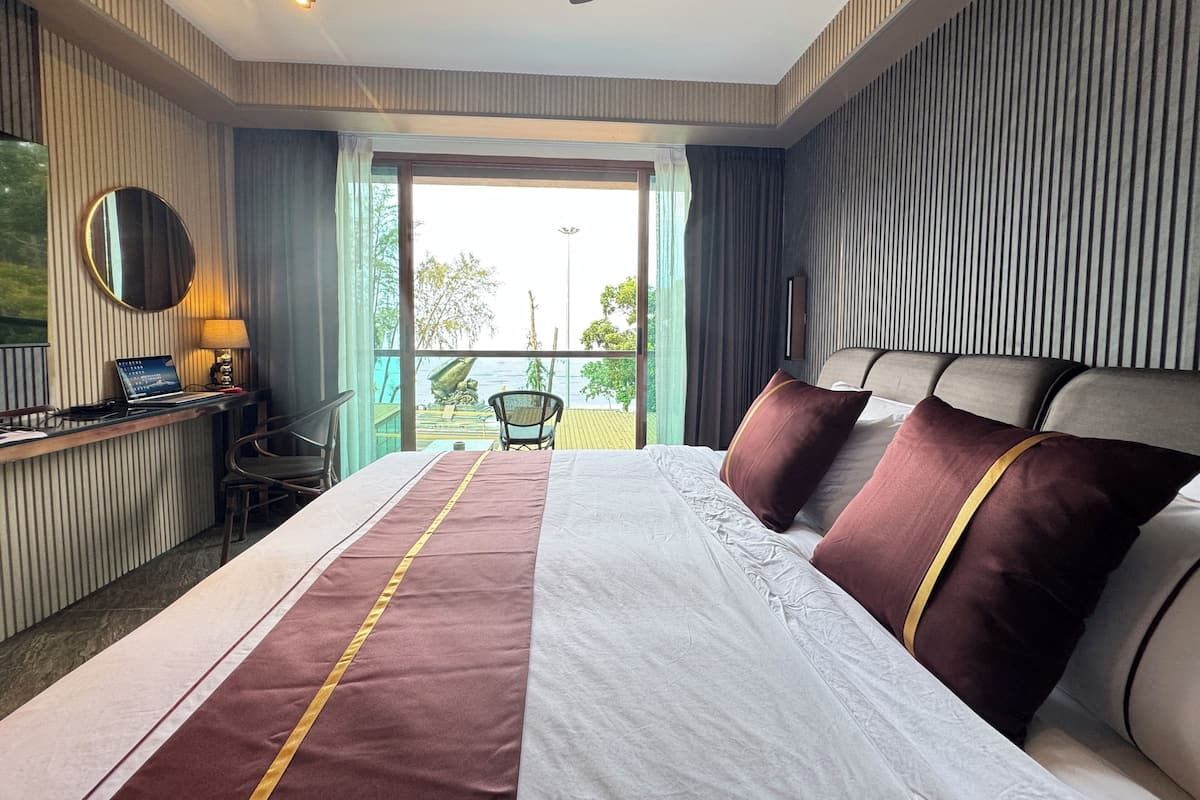 Habitación de hotel con cama, escritorio con una laptop, una silla y vistas al exterior.