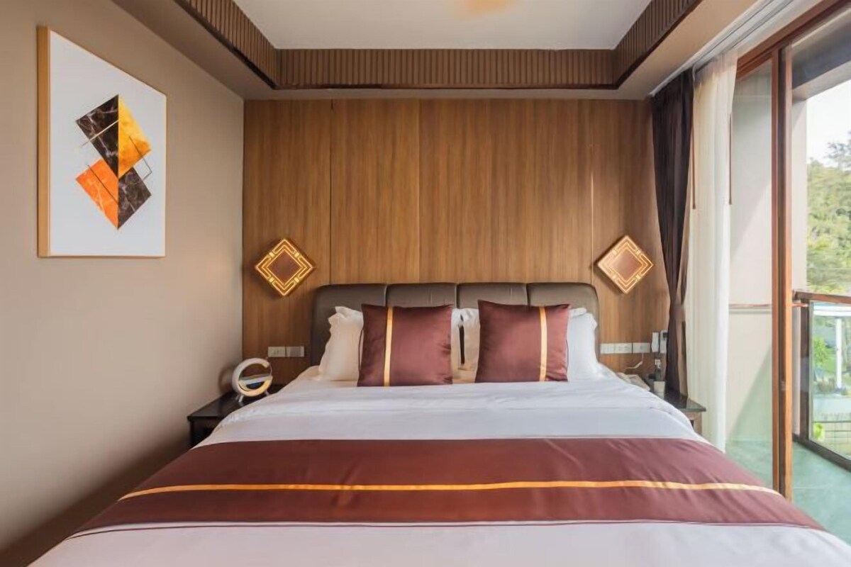 Habitación de hotel con una cama grande, cabecero de madera y vistas al exterior.
