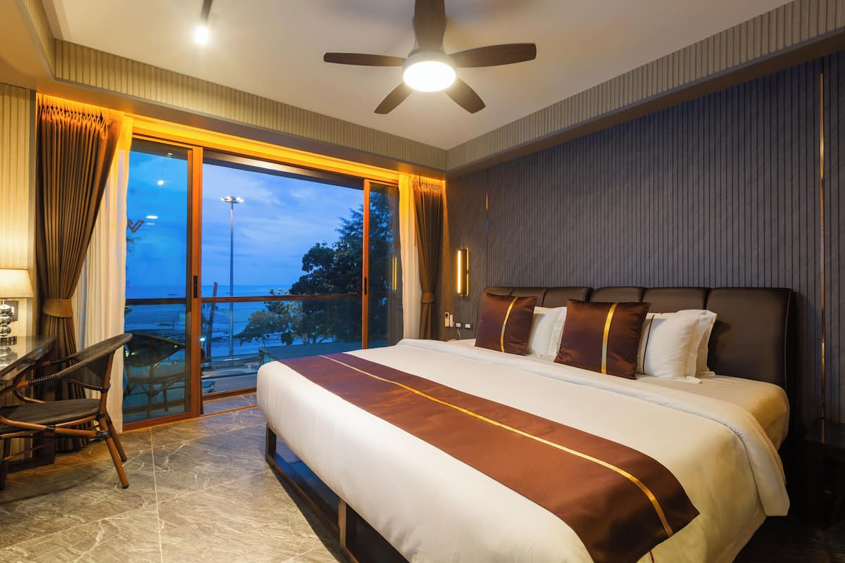 Habitación de hotel con una cama grande, un escritorio y una silla. Tiene un balcón con vistas al exterior.