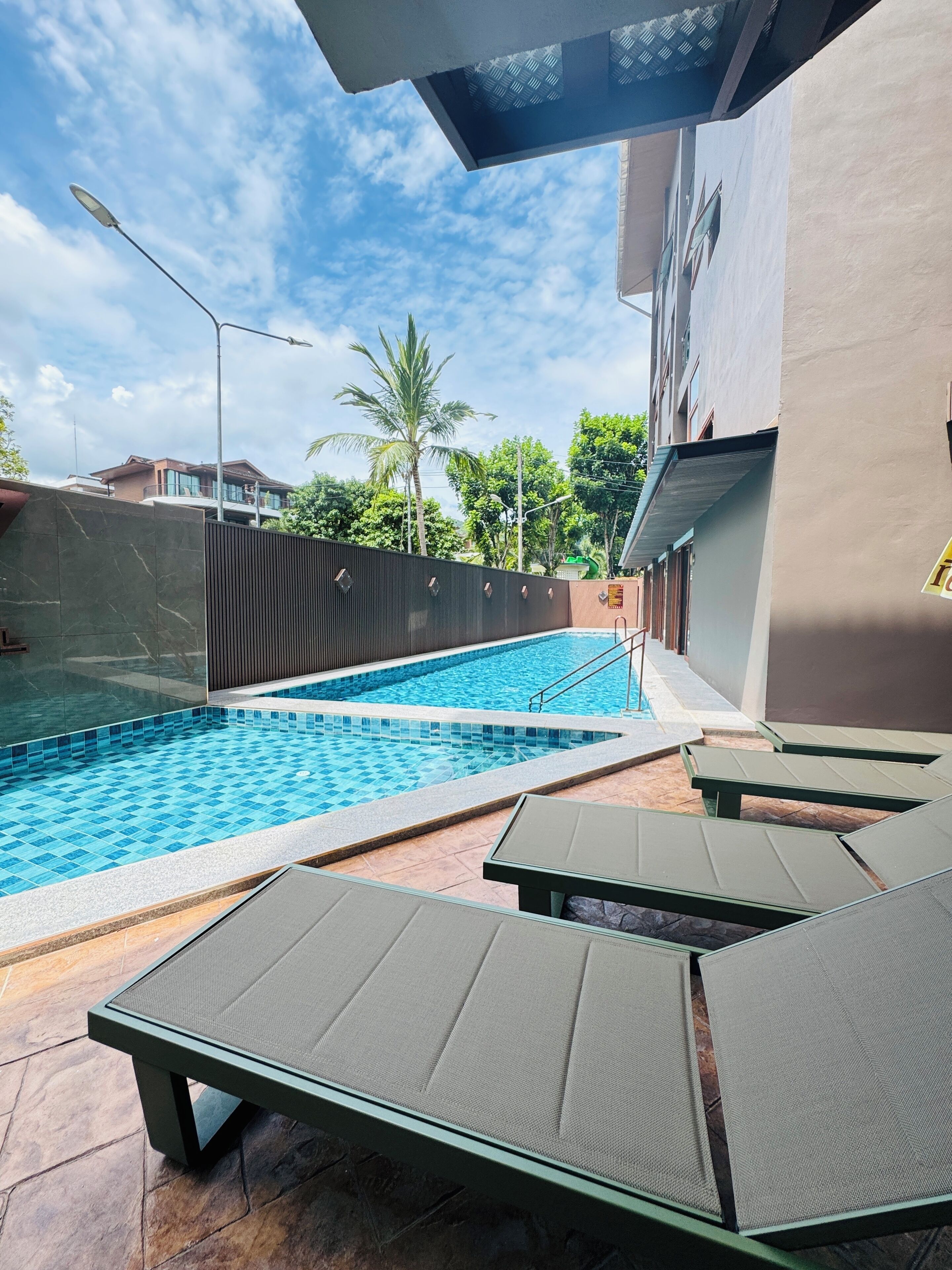 A swimming pool with lounge chairs and a tiled deck.