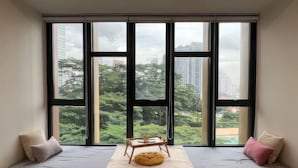 A room with a large window overlooking a cityscape and greenery.