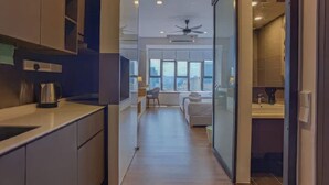 A modern kitchen with a coffee maker, a dining area with a table and chairs, and a view of the city through large windows.