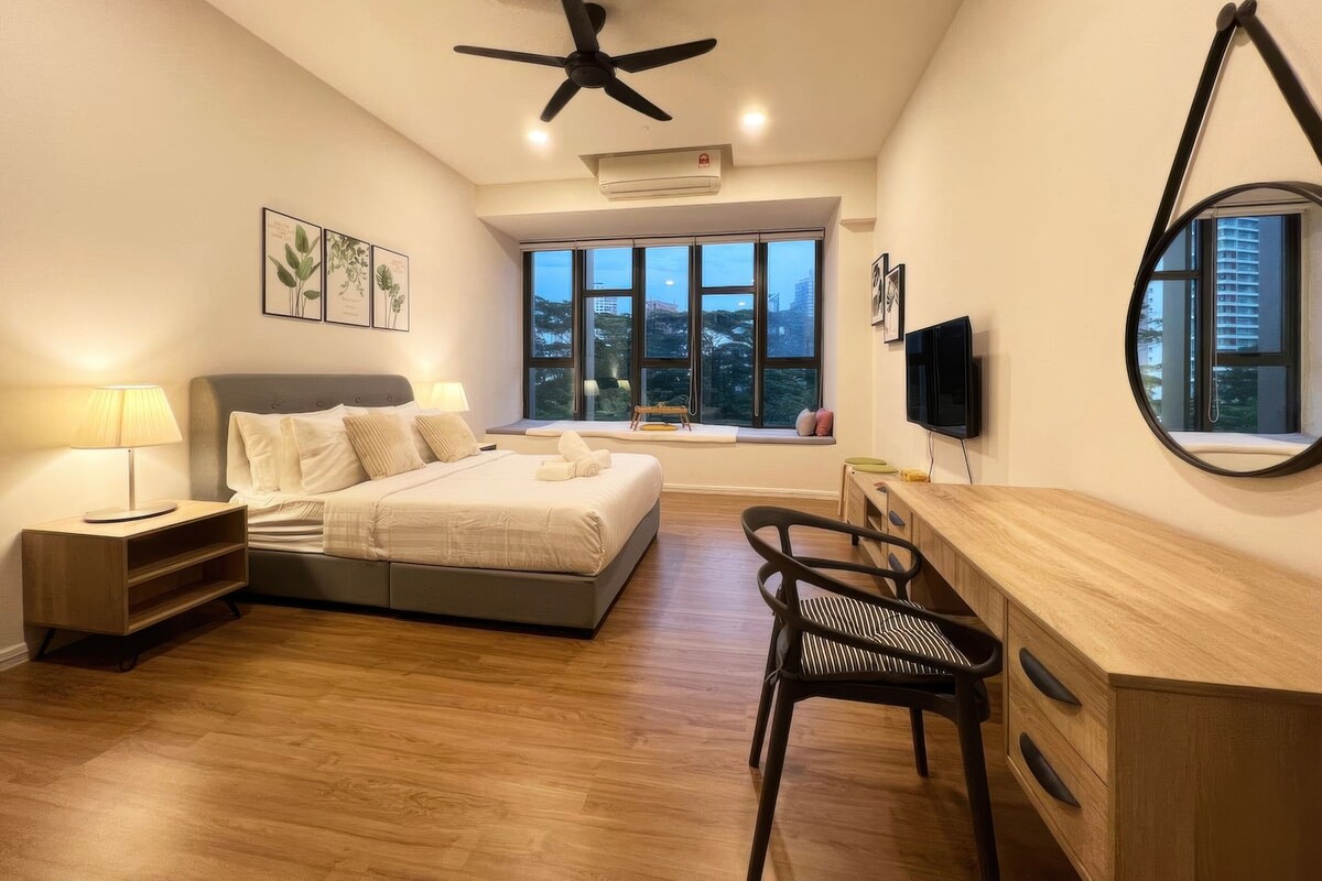A modern bedroom with a bed, bedside tables, a desk, a chair, a ceiling fan, and large windows.