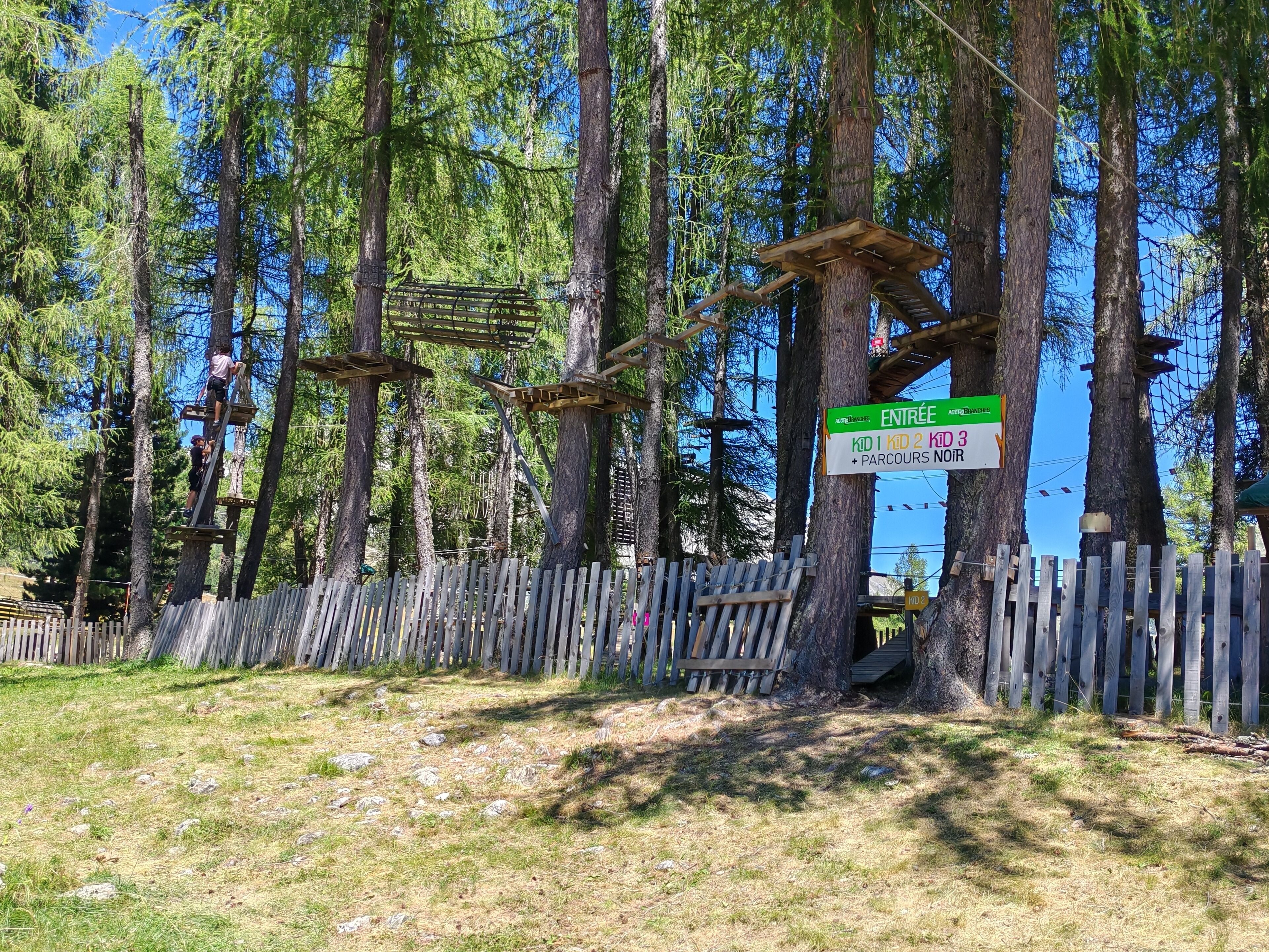 Et skovområde med trælegkonstruktioner og et skilt, der angiver adgang for børn i alderen 1 til 3 år.