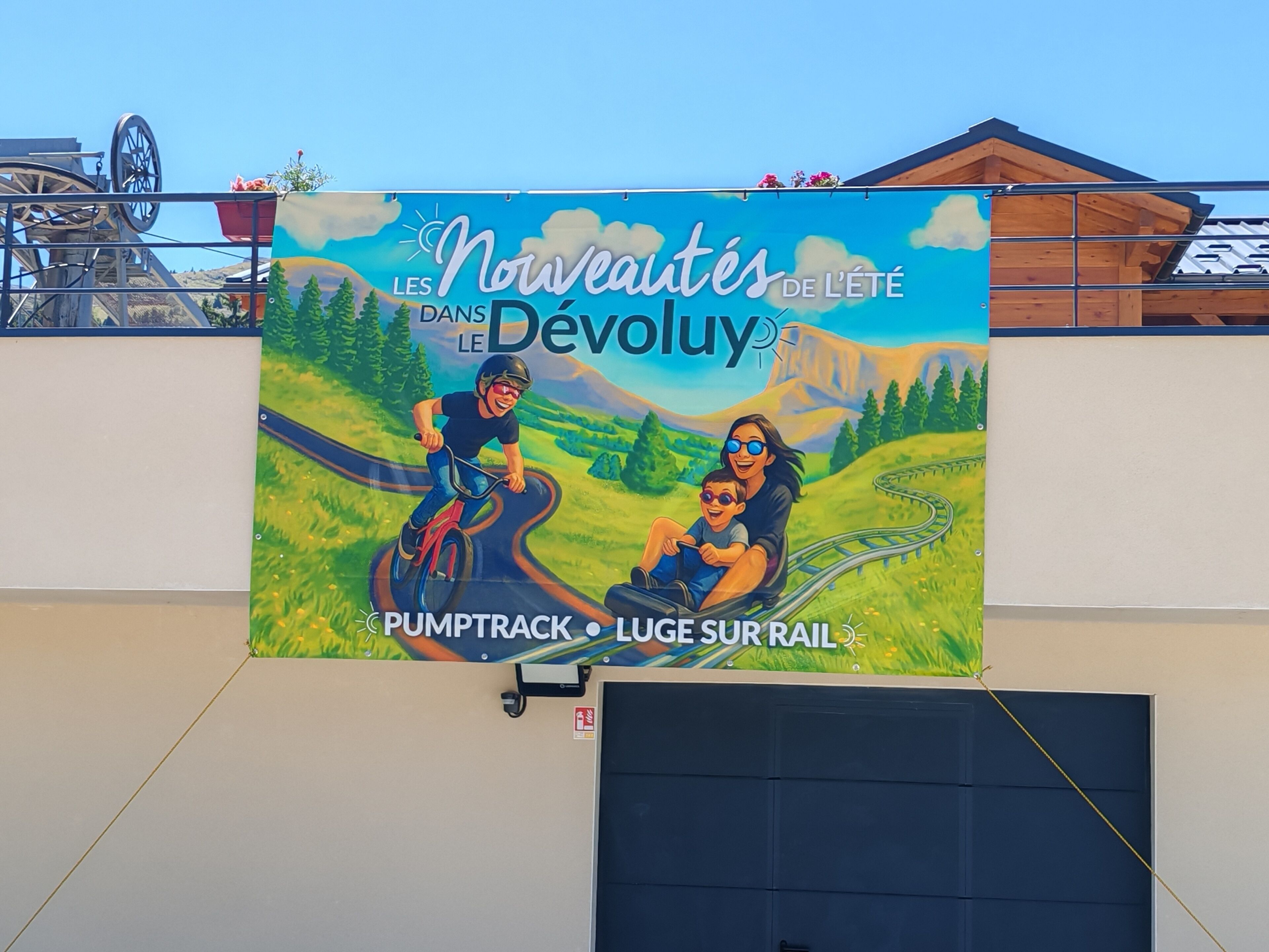 Un mural publicitario de un evento ciclista con un paisaje pintoresco y una montaña rusa al fondo.
