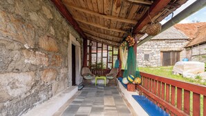 A covered porch with stone walls, a wooden ceiling, and a bench. - 4-bedroom house in charming Gračac with WiFi (Gračac)