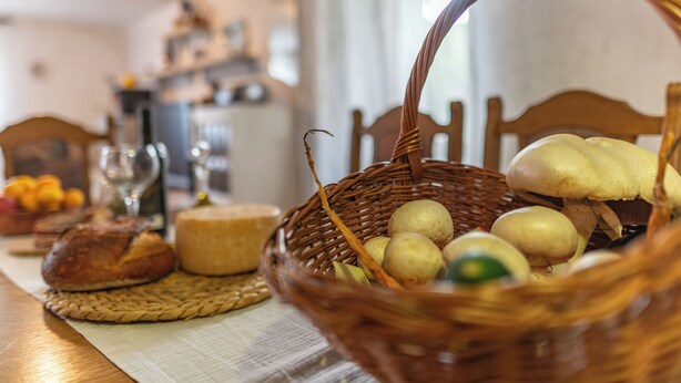A dining table with a basket of bread, cheese, and potatoes. - 4-bedroom house in charming Gračac with WiFi (Gračac)