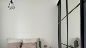 A modern bedroom with a bed, bedside tables, and a large window. - Twin with city views (Helsinki)
